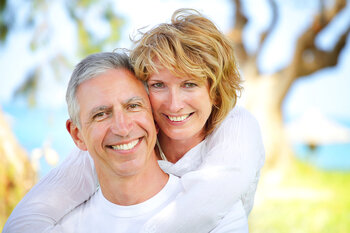 mature couple smiling outdoors near beach dental implants Wallace, NC